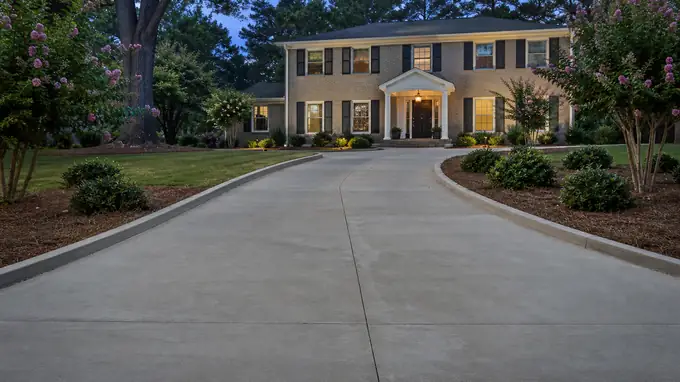concrete construction services completed by a local contractor at a tan-brick colonial in Alpharetta, GA, at blue hour.