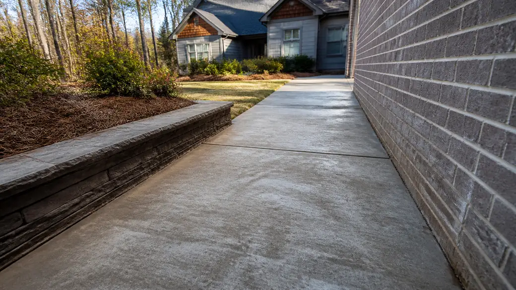 stamped concrete installation completed by a local contractor at a grey split-level home in Alpharetta, GA, under low winter sun.